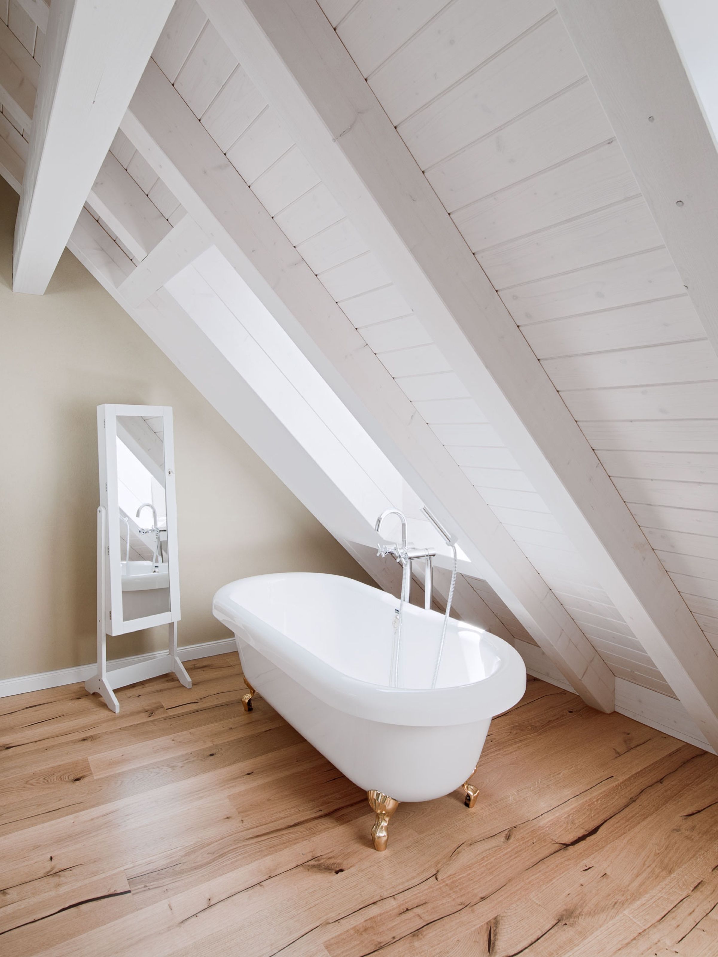 Freistehende Wanne unter weiss gestrichener Holzschalung in der Dachschräge