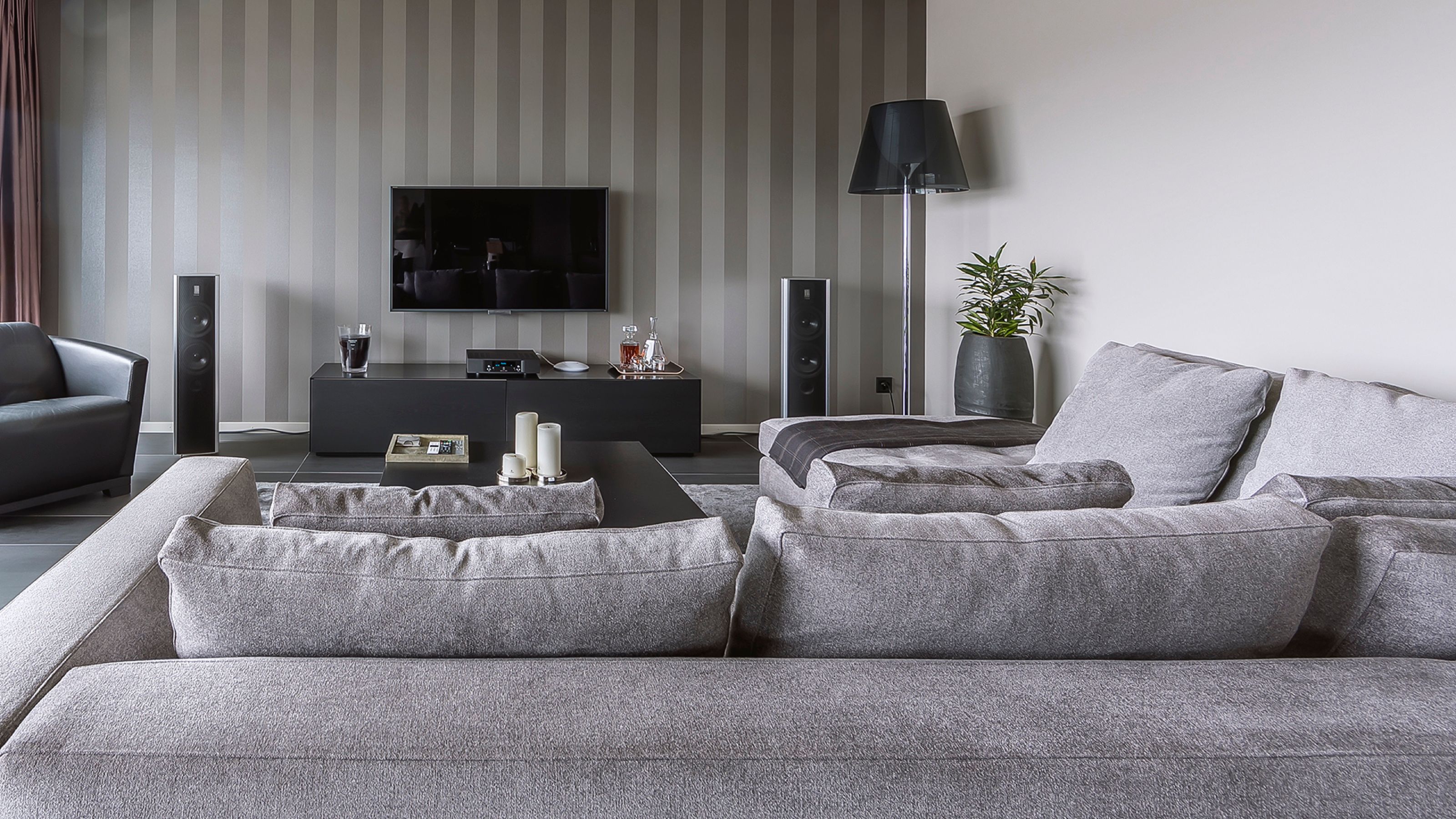 Wohnzimmer mit grauem Sofa und gestreifter Tapetenwand